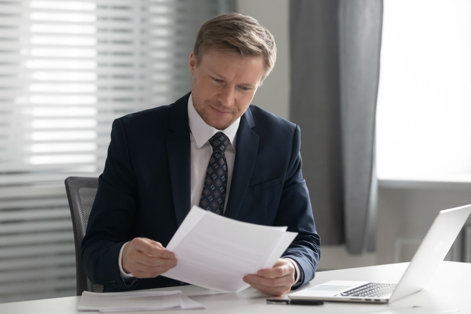 Man In Suit Holding Read Document Paper Report Sit At Office Desk